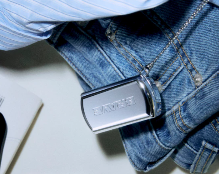 Braye metal lip compact hanging from a chain on denim jeans
